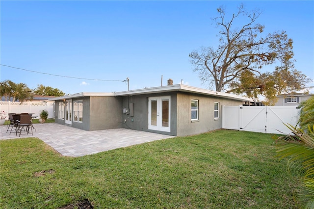 rear view of property featuring french doors, a patio, stucco siding, a gate, and fence