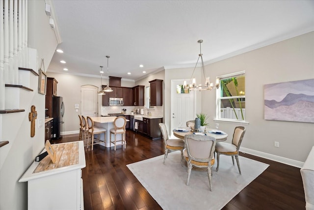 dining room with dark wood-type flooring, ornamental molding, sink, and a notable chandelier