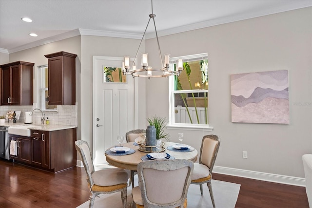 dining room featuring an inviting chandelier, sink, dark wood-type flooring, and ornamental molding