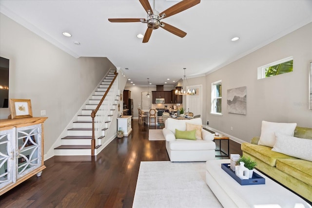 living room featuring ornamental molding, dark wood-type flooring, and ceiling fan with notable chandelier