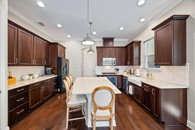 kitchen featuring a kitchen island, appliances with stainless steel finishes, sink, dark hardwood / wood-style flooring, and hanging light fixtures