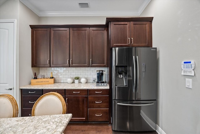 kitchen with stainless steel fridge, light stone counters, tasteful backsplash, ornamental molding, and dark hardwood / wood-style flooring