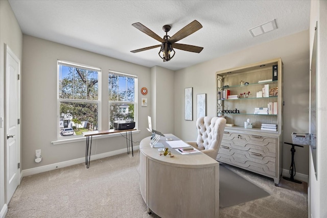 carpeted home office featuring a textured ceiling and ceiling fan