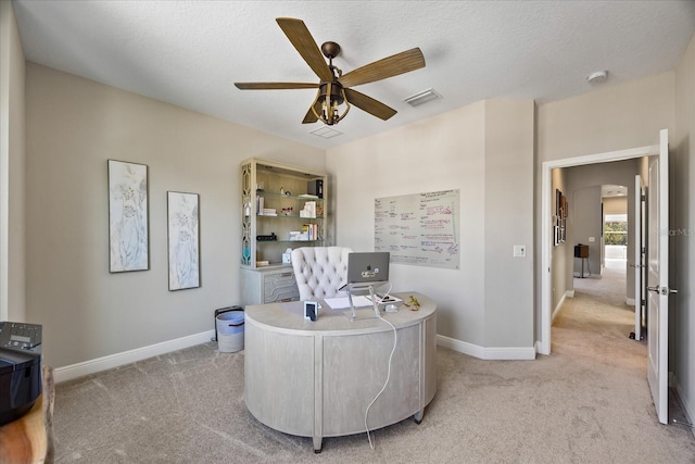 home office featuring ceiling fan, light colored carpet, and a textured ceiling