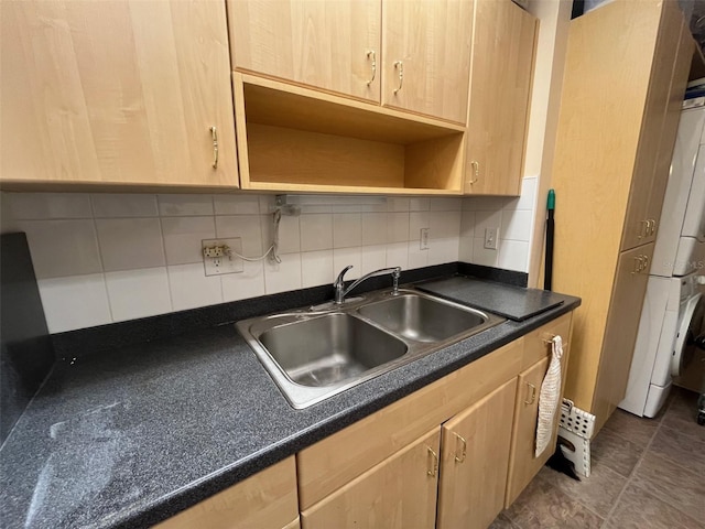 kitchen with tasteful backsplash, dark countertops, light brown cabinetry, open shelves, and a sink