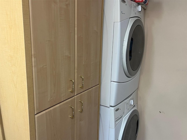 laundry area featuring cabinet space and stacked washer / dryer