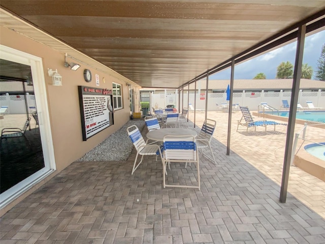 view of patio featuring a community pool, fence, and outdoor dining area