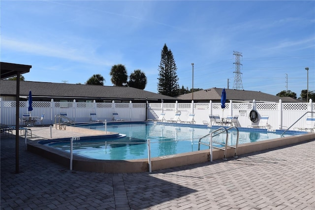 community pool with a patio area and fence