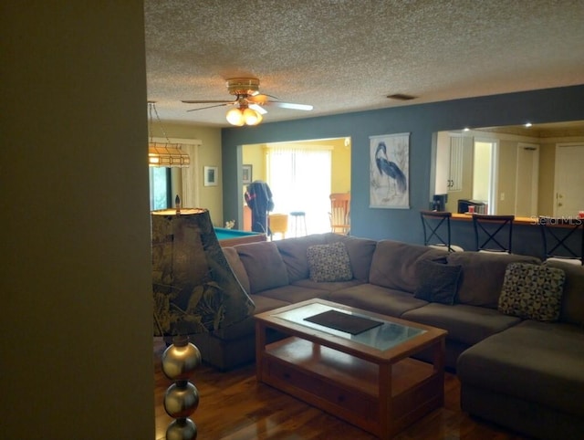 living room featuring ceiling fan, hardwood / wood-style floors, and a textured ceiling