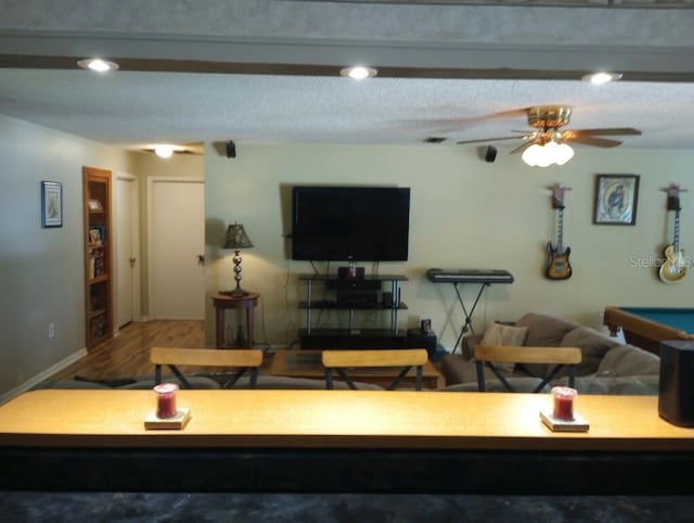 living room featuring ceiling fan, hardwood / wood-style floors, and a textured ceiling