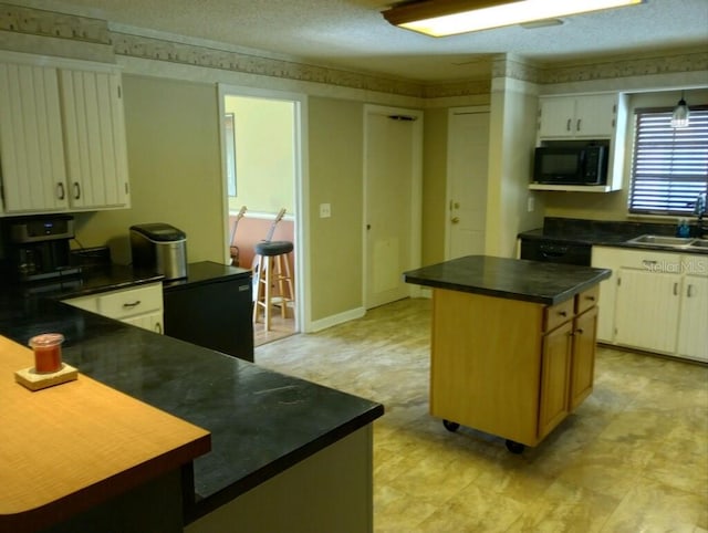 kitchen with sink, a textured ceiling, and a kitchen island