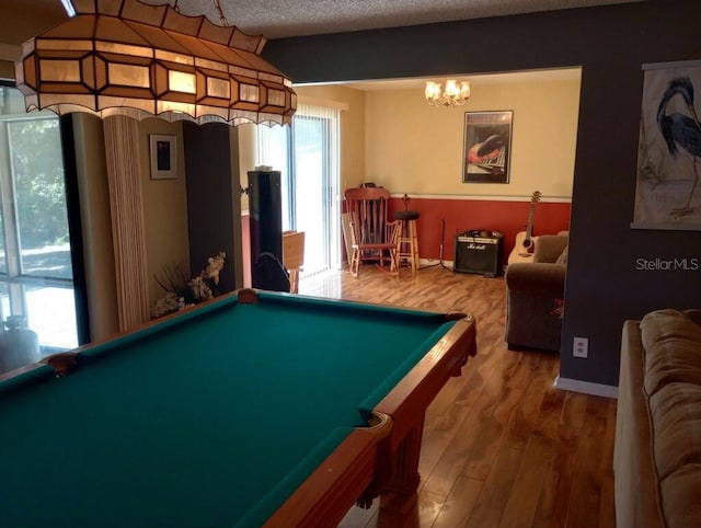 rec room with pool table, plenty of natural light, hardwood / wood-style floors, and a textured ceiling