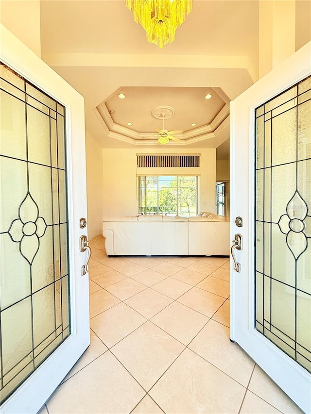 entrance foyer featuring a tray ceiling and light tile patterned floors