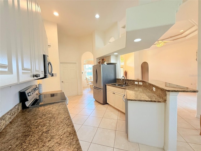 kitchen with sink, appliances with stainless steel finishes, a kitchen breakfast bar, dark stone counters, and white cabinets