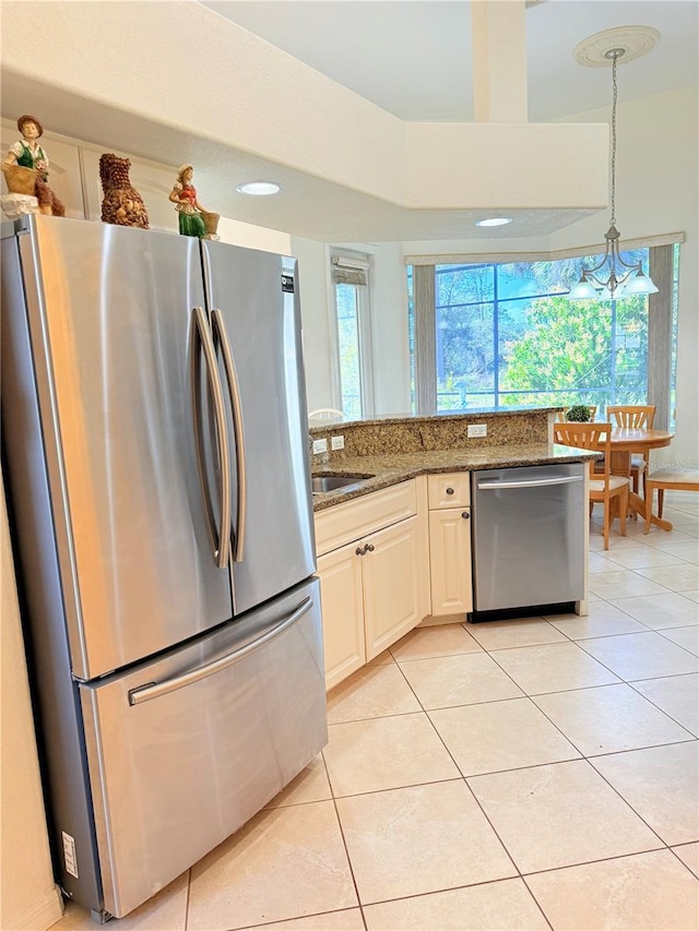 kitchen with sink, stone counters, white cabinetry, hanging light fixtures, and stainless steel appliances