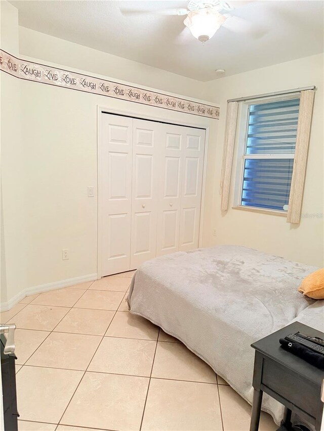 tiled bedroom with ceiling fan and a closet