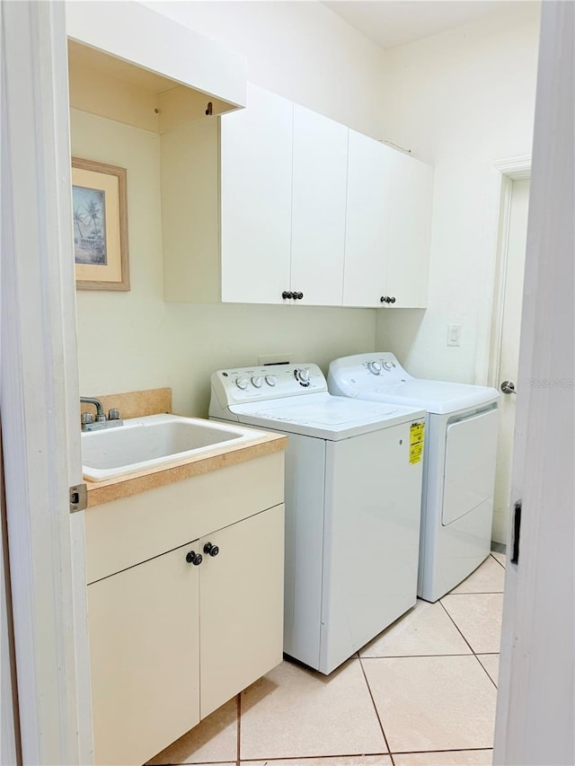 laundry area featuring cabinets, light tile patterned flooring, sink, and washing machine and clothes dryer