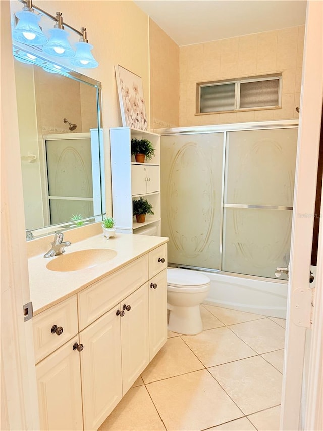 full bathroom with bath / shower combo with glass door, toilet, tile patterned floors, and vanity