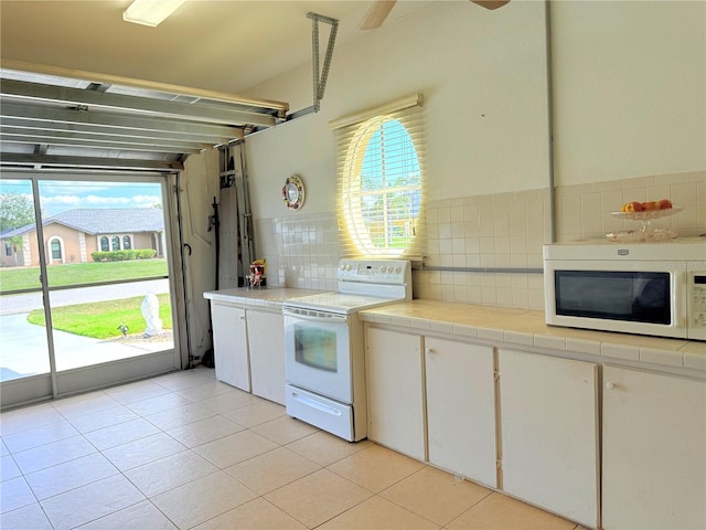 kitchen with light tile patterned floors, white appliances, white cabinets, decorative backsplash, and tile countertops