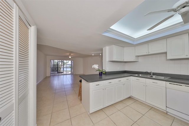 kitchen with dark countertops, light tile patterned floors, white dishwasher, a ceiling fan, and a sink