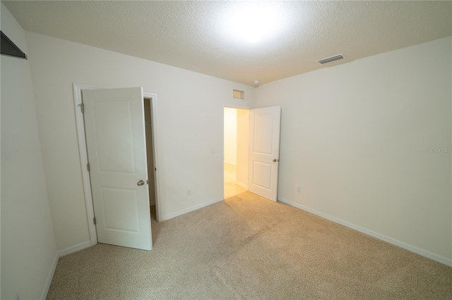 unfurnished bedroom with light carpet and a textured ceiling