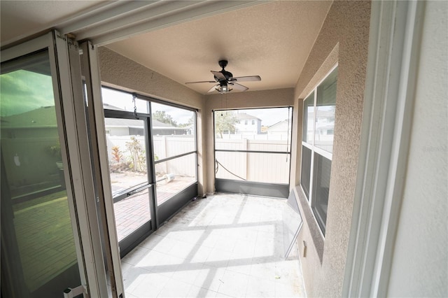 unfurnished sunroom with ceiling fan