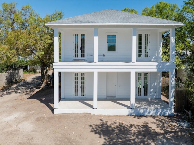 rear view of property with french doors, a patio, and roof with shingles