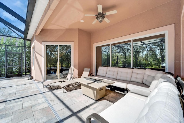 view of patio featuring a lanai, an outdoor living space with a fire pit, and ceiling fan