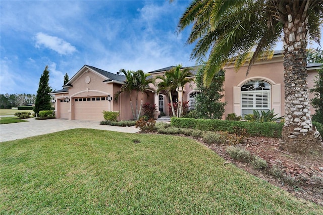 mediterranean / spanish house with a garage, a front lawn, decorative driveway, and stucco siding