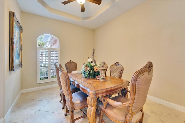 dining area featuring light tile patterned flooring, ceiling fan, and a raised ceiling