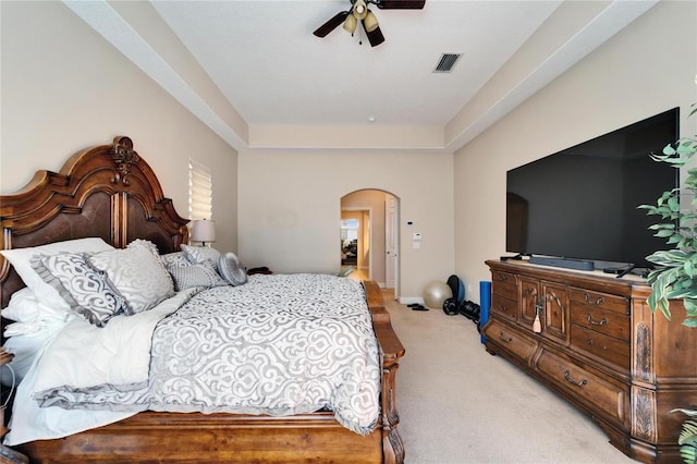 bedroom with arched walkways, light colored carpet, visible vents, a ceiling fan, and baseboards