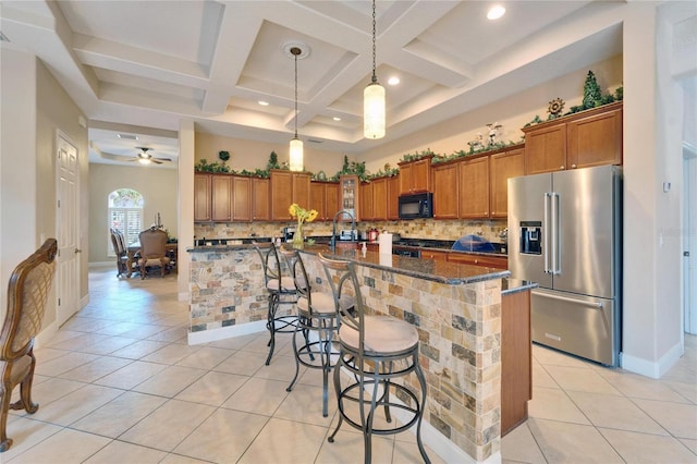 kitchen featuring brown cabinetry, black microwave, a kitchen island with sink, and high end refrigerator