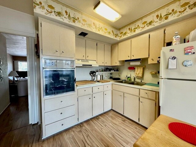 kitchen featuring light hardwood / wood-style flooring, sink, oven, white refrigerator, and gas stovetop