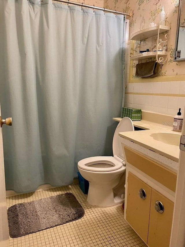 bathroom with tile patterned floors, tile walls, toilet, and vanity