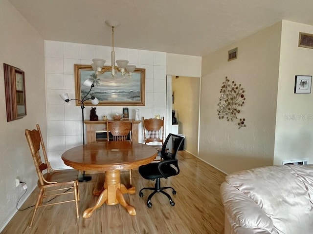 dining area with light hardwood / wood-style flooring and a chandelier