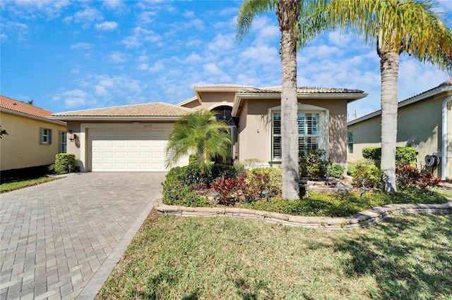 view of front of house featuring stucco siding, a tile roof, decorative driveway, and a garage