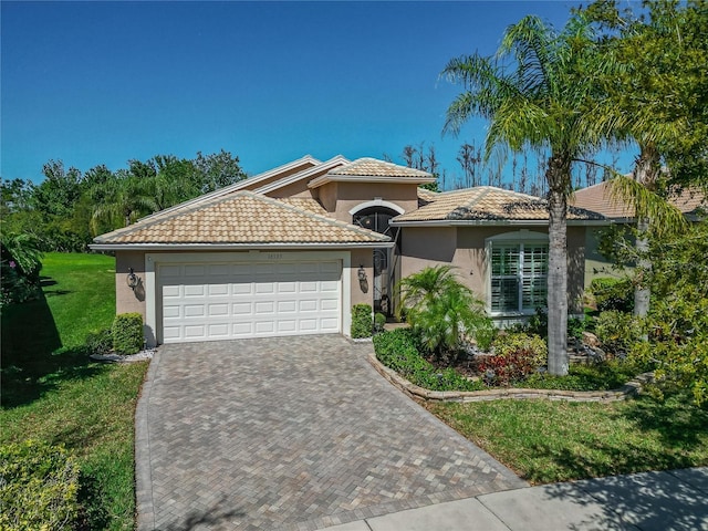 view of front of property with stucco siding, a front lawn, decorative driveway, a garage, and a tiled roof