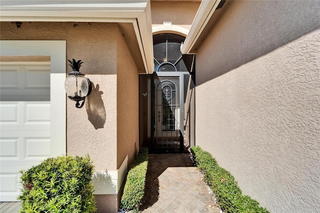 view of exterior entry featuring stucco siding and an attached garage