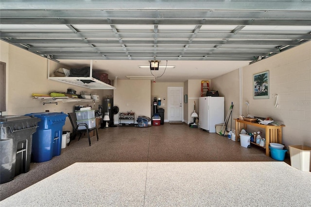 garage with concrete block wall, a garage door opener, water heater, and freestanding refrigerator