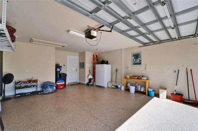 garage featuring concrete block wall, a garage door opener, and freestanding refrigerator