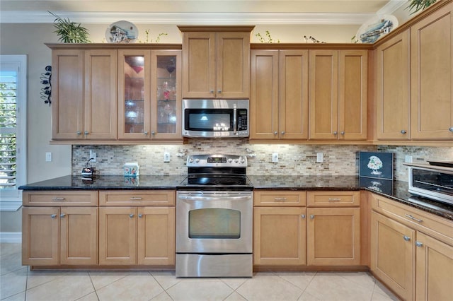 kitchen featuring decorative backsplash, dark stone countertops, stainless steel appliances, and crown molding