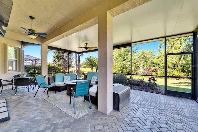 view of patio with glass enclosure, an outdoor living space with a fire pit, and ceiling fan