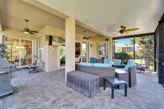 view of patio / terrace with glass enclosure, an outdoor hangout area, and a ceiling fan