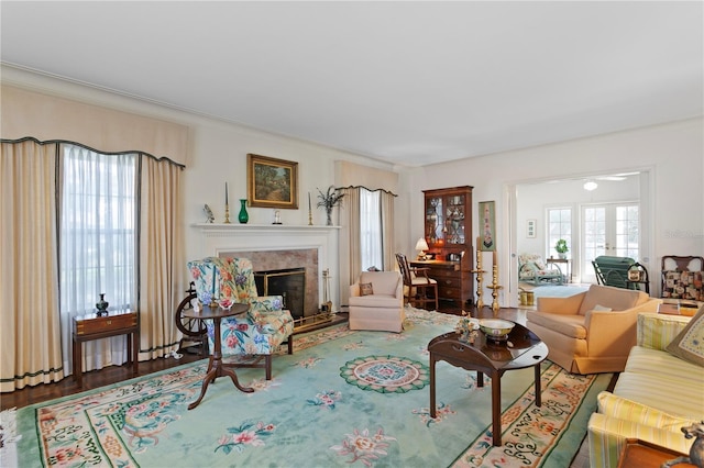 living area with wood finished floors, french doors, a wealth of natural light, and a high end fireplace