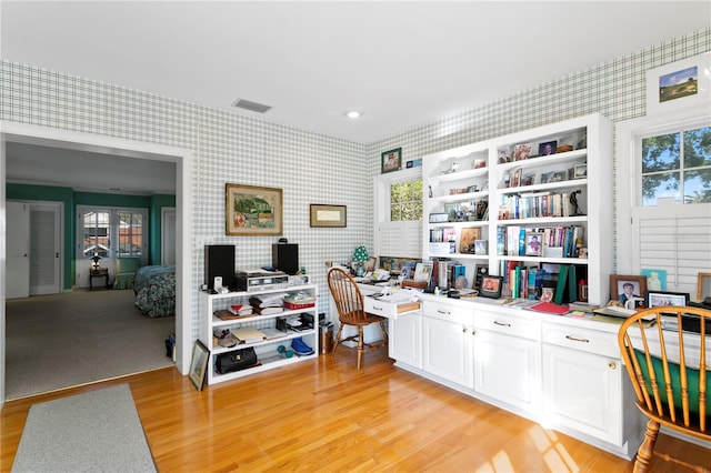 home office with wallpapered walls, visible vents, light wood-style floors, and built in study area