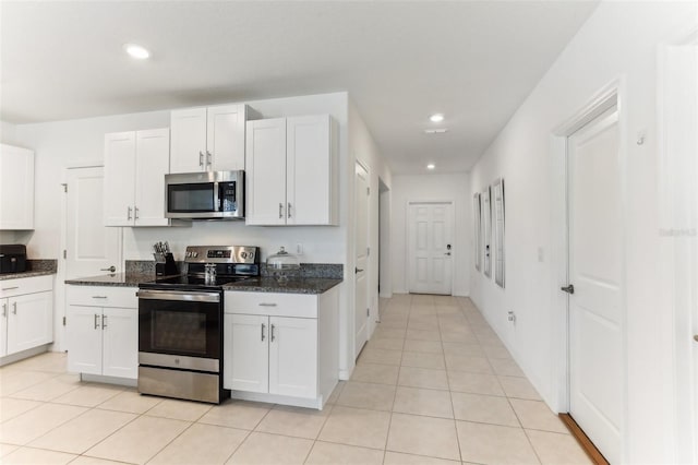 4323 Trotters Way, Lakeland, FL 33801 - kitchen with dark stone countertops, light tile patterned floors, white cabinets, and appliances with stainless steel finishes