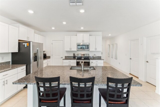 4323 Trotters Way, Lakeland, FL 33801 - kitchen featuring an island with sink, white cabinetry, dark stone countertops, a kitchen bar, and stainless steel appliances