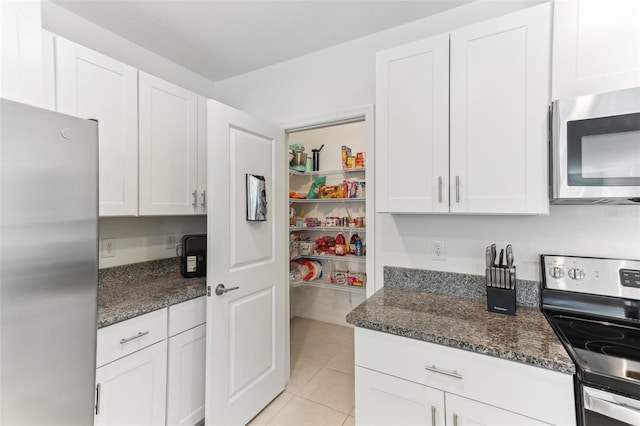 4323 Trotters Way, Lakeland, FL 33801 - kitchen featuring white cabinetry, appliances with stainless steel finishes, light tile patterned floors, and dark stone countertops