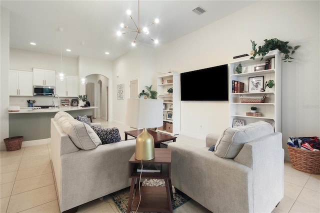 living room featuring a notable chandelier, sink, a high ceiling, and light tile patterned floors