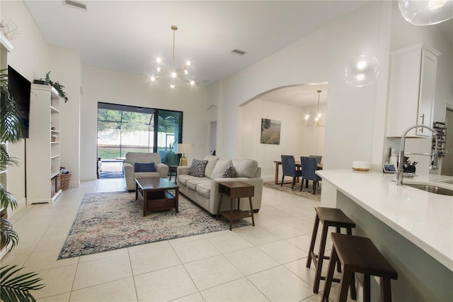 living room with sink, light tile patterned floors, high vaulted ceiling, and a chandelier